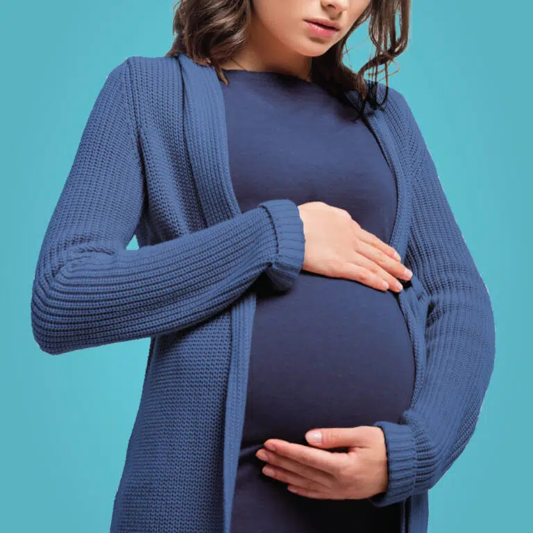 pregnant woman holding her belly wearing dress and long sweater